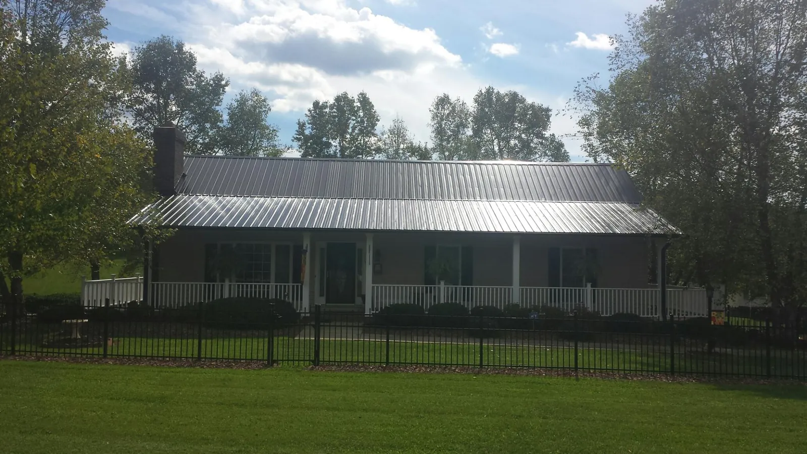 Gray metal roof on a brick ranch with a full width front porch — Gutter Guard Installation work by our crew in Eunice