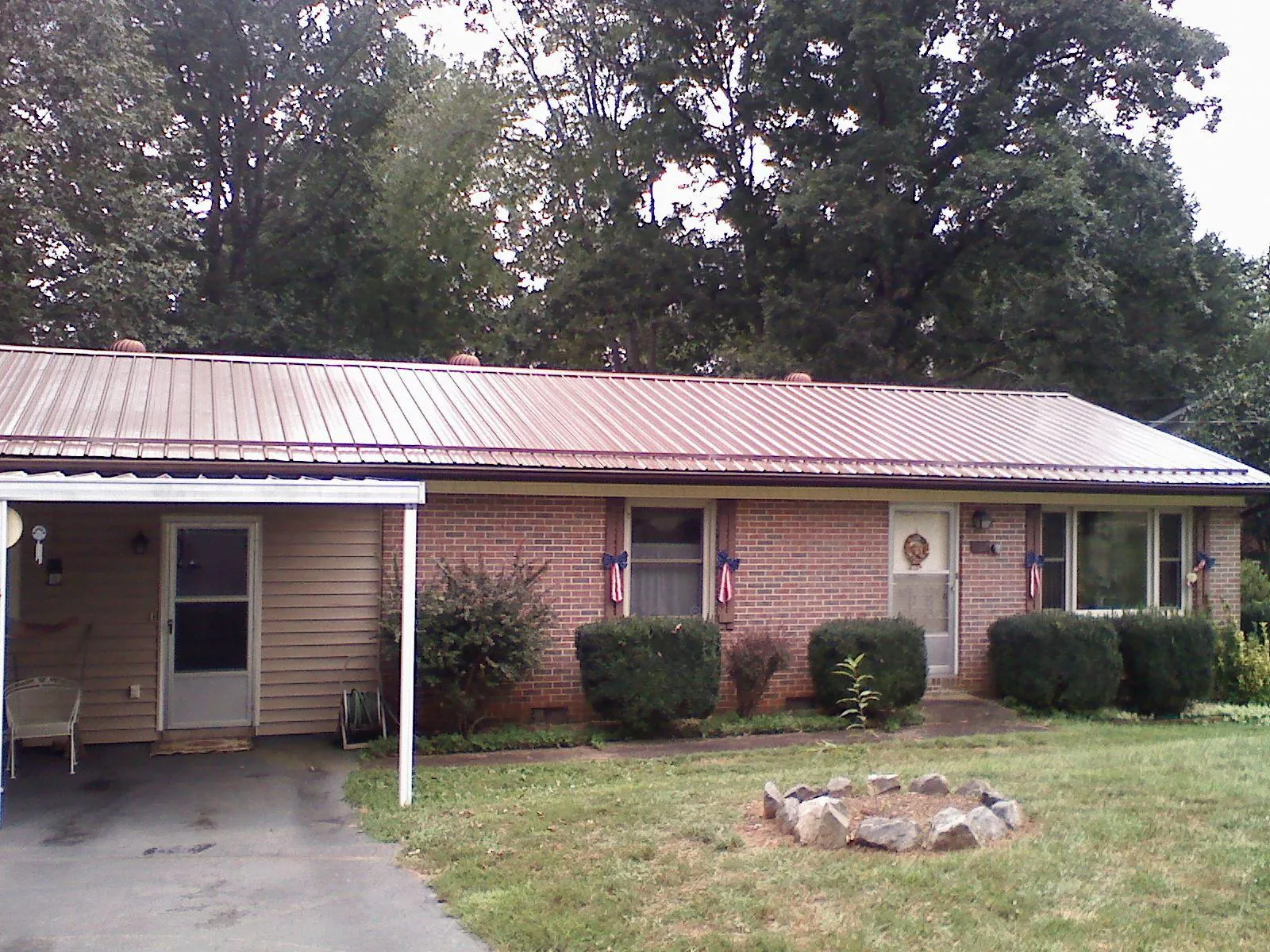 Bronze metal roof and carport on a brick ranch home — Roof Repair work by our crew in Eunice