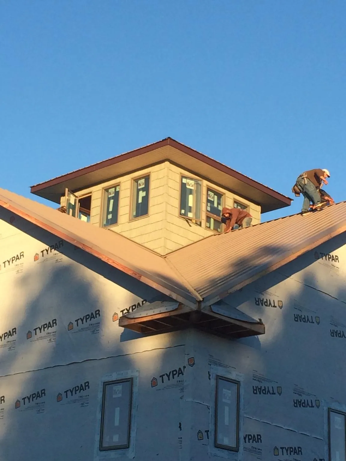 Roofers working around a rooftop cupola on a new metal roof at sunset — Roof Waterproofing in Eunice by Roofing Brothers
